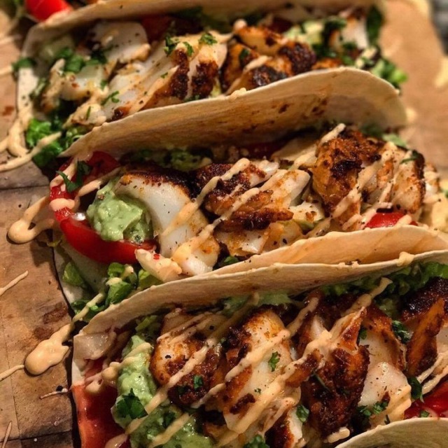 Three blackened fish tacos with guacamole and crema